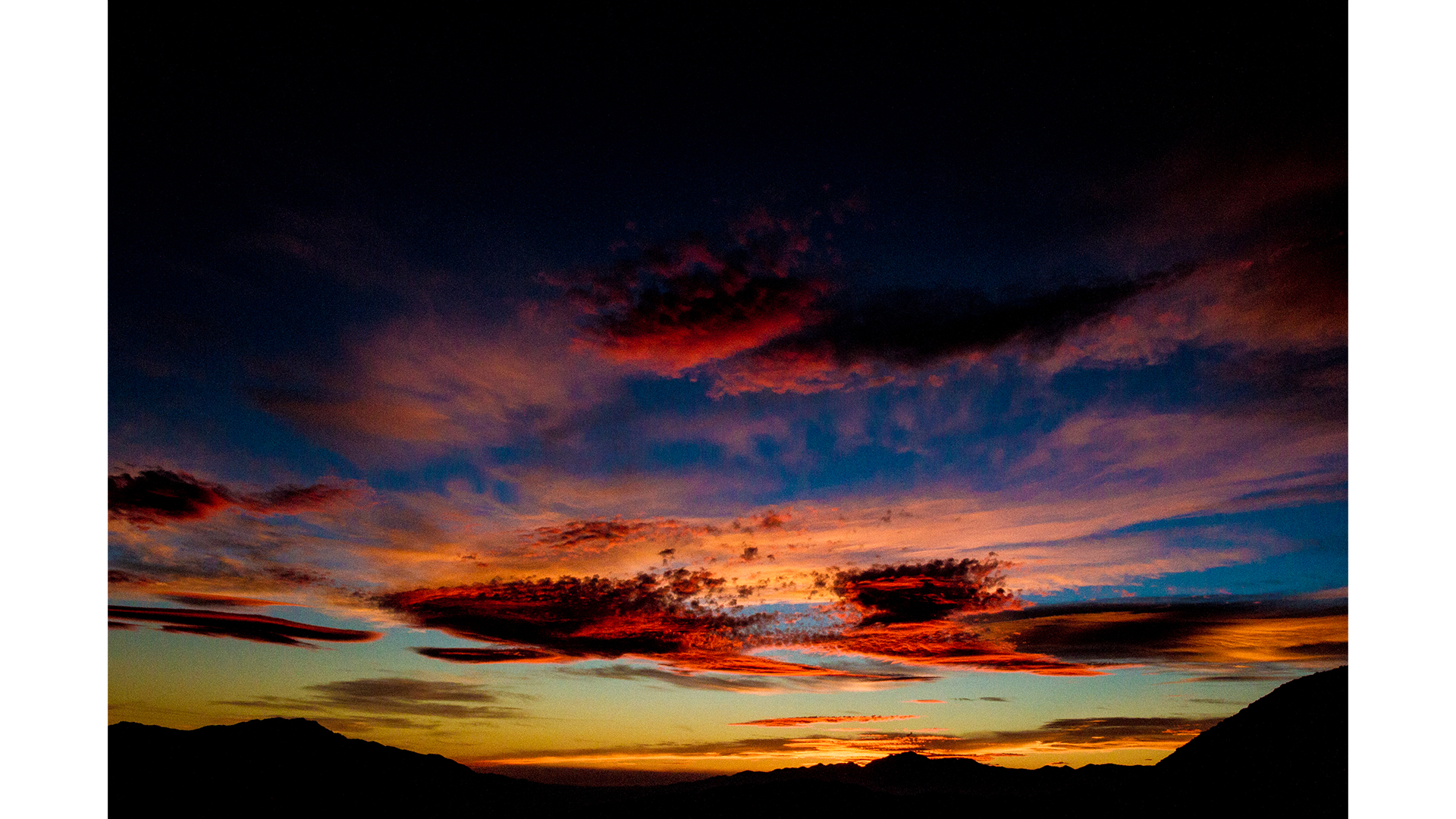  a grainy sky, filled with light and coulds that catch yellows, reds and blues